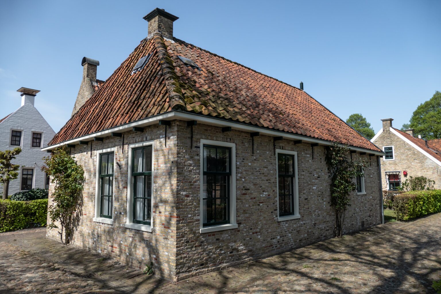 Ein historisches Backsteinhaus mit rotem Ziegeldach in der Festung Bourtange unter blauem Himmel.