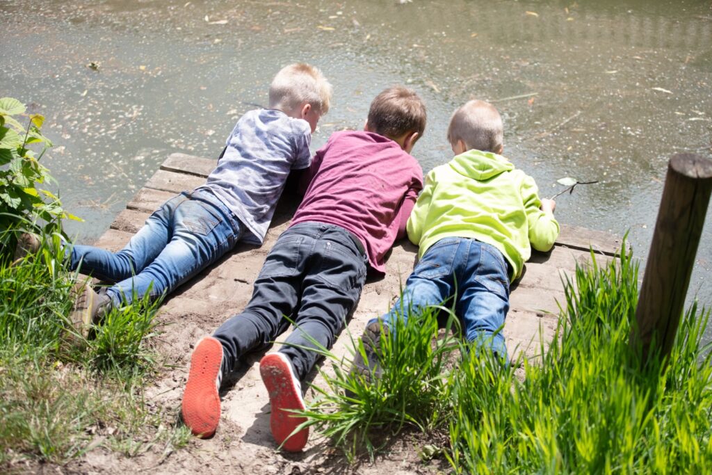 Familienhotel Gut Landegge im Emsland: Drei Jungs liegen auf dem Steg und schauen ins Wasser