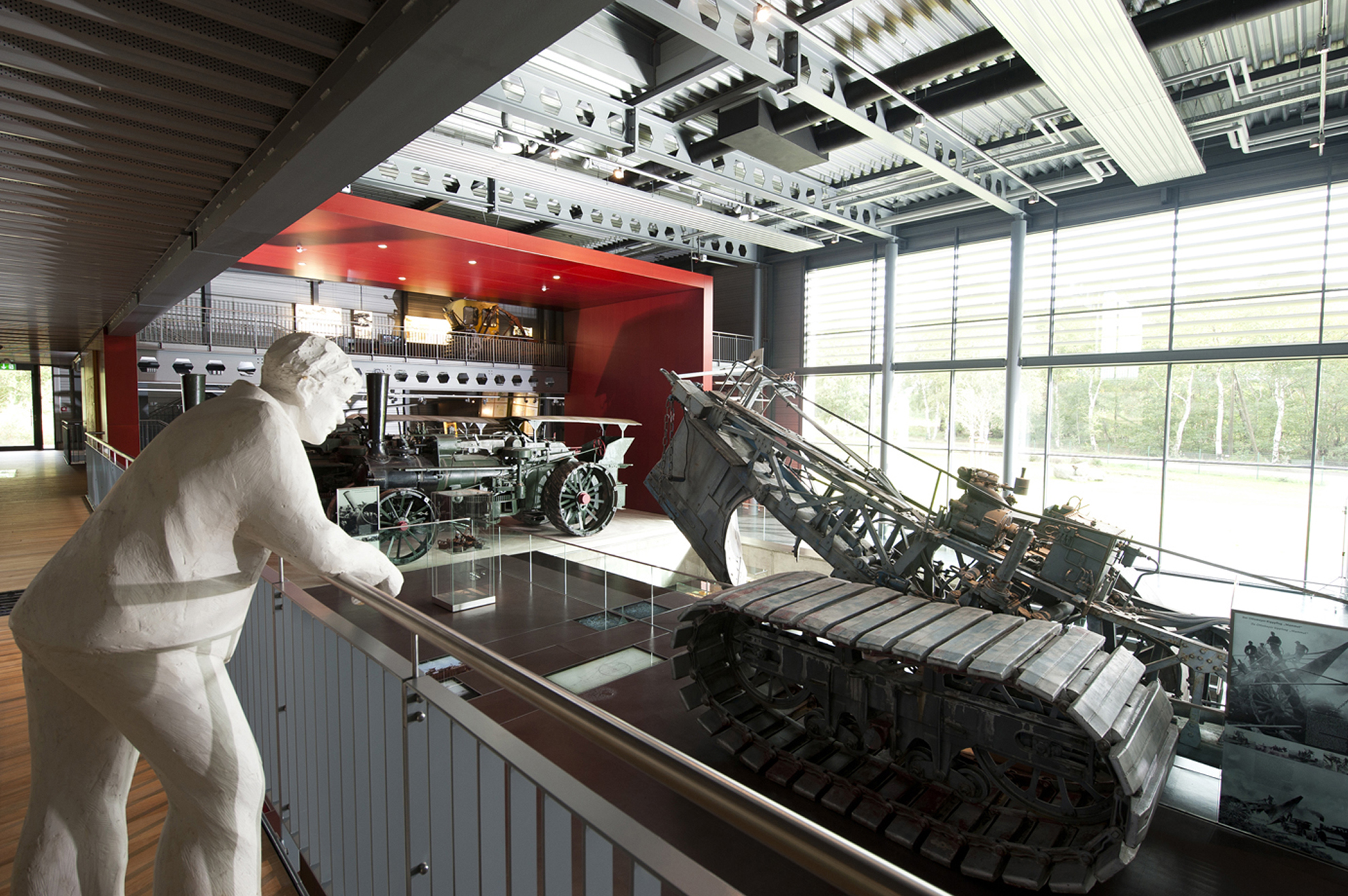 Im Emsland-Moormuseum stehen eine weiße Mammutfigur und historische Landmaschinen in einer hellen Ausstellungshalle.